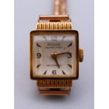 A ladies 18 ct gold Mithra wristwatch with a roll gold strap, 17 jewel Swiss movement.