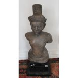 A life size torso South Asian stone figure of Shiva, mounted on a display plinth.