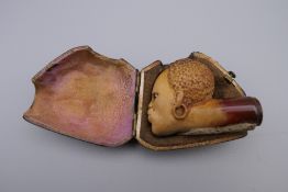 A late 19th century meerschaum pipe in the form of an African head, in original case. 5.5 cm wide.