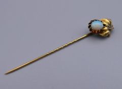 An unmarked gold and opal stick pin. 6 cm high. 1.9 grammes total weight.