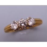 An 18 ct gold three stone diamond ring. Ring size U. 4.1 grammes total weight.