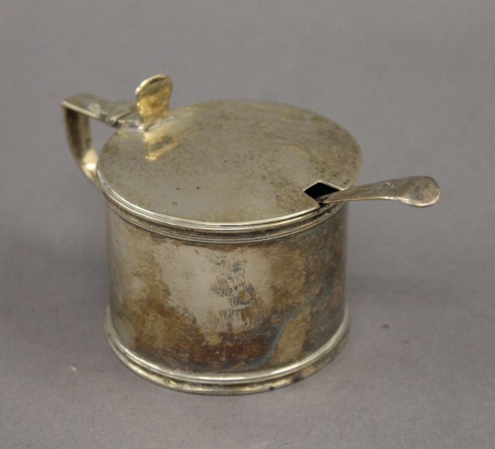 A silver mustard pot with blue glass liner and a silver spoon. 6 cm high. 3.9 troy ounces.