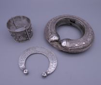 Three Eastern white metal bangles, two probably unmarked silver. The largest 12.5 cm diameter.