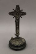 A Continental plated crucifix on ebonised stand. 23.5 cm high overall.
