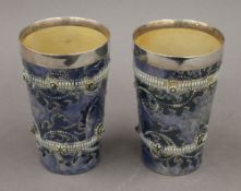 A pair of Doulton Lambeth stoneware George Tinworth silver rimmed beakers. 13.5 cm high.