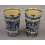 A pair of Doulton Lambeth stoneware George Tinworth silver rimmed beakers. 13.5 cm high.