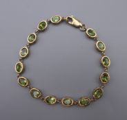 A 9 ct gold and peridot tennis bracelet. 18 cm long.