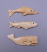 Three bone carvings; one a whale, one a dolphin and one a fish. The former 8 cm long.