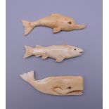 Three bone carvings; one a whale, one a dolphin and one a fish. The former 8 cm long.