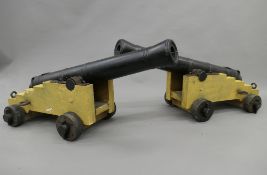 A pair of early 20th century iron mounted wooden model canons. Each approximately 103 cm long.