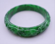 A carved apple green jade bangle. Exterior 7 cm diameter.