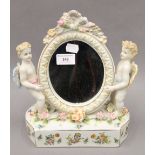 A porcelain mirror decorated with putti. 26 cm high.