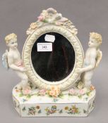 A porcelain mirror decorated with putti. 26 cm high.