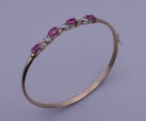 A 9 K gold diamond and ruby bracelet. 6 cm diameter. 4.7 grammes total weight.
