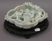 A Chinese green and white jade brush washer mounted on a detachable wooden base. 21 cm wide.