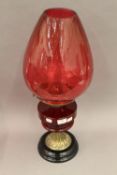 A Victorian oil lamp with ruby glass reservoir and cranberry glass shade. 63 cm high.