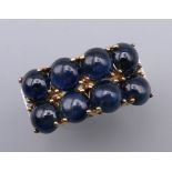 An unusual 9 ct gold ring set with eight cabochon sapphires flanked by six small diamonds.