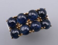 An unusual 9 ct gold ring set with eight cabochon sapphires flanked by six small diamonds.