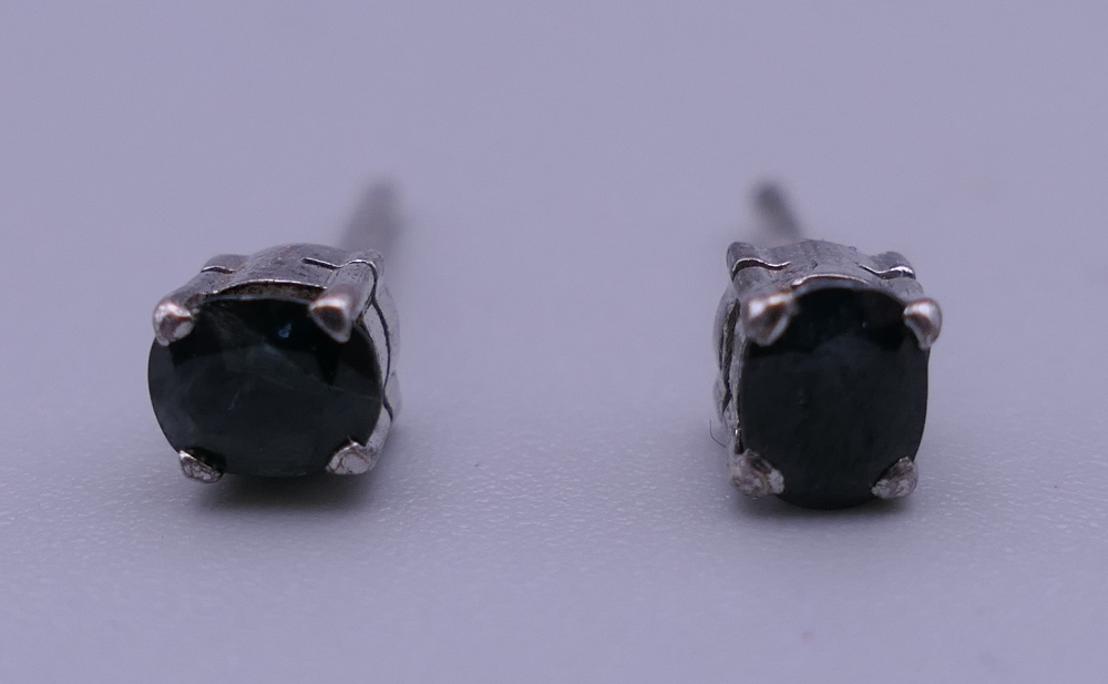 A pair of white gold and sapphire ear studs. Each 4 mm high.