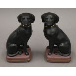 A pair of painted plaster models of black Labradors. 20 cm high.