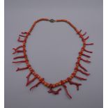 A red coral bead and twig coral necklace with silver clasp. 51 cm long.