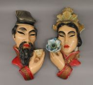 A pair of plaster wall masks depicting a Chinese man and woman.