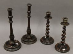 A pair of oak barley twist candlesticks and a pair of stained beech candlesticks.