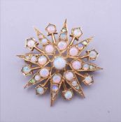 A 9 ct gold opal set starburst form pendant/brooch. 2.75 cm wide. 5.4 grammes total weight.