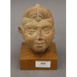 An Indian terracotta head on wooden display stand. 15.5 cm high.