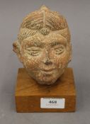 An Indian terracotta head on wooden display stand. 15.5 cm high.