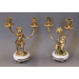 A pair of bronze cherub candelabra. 29.5 cm high.