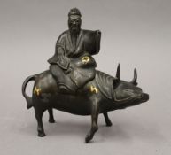 A Chinese bronze censer formed as a man sitting on a cow. 18 cm high.