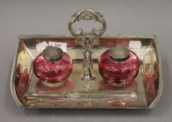 A silver plated desk stand set with cranberry glass inkwells. 28.5 cm wide.