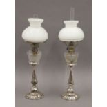 A pair of Victorian silver plated oil lamps, with cut glass reservoirs and opaline shades.