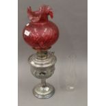 A Victorian silver plated oil lamp and cranberry glass shade. 56 cm high.