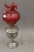 A Victorian silver plated oil lamp and cranberry glass shade. 56 cm high.