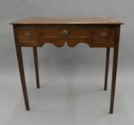 A George III oak three-drawer side table. 81.5 cm wide.