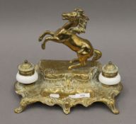 A porcelain mounted brass inkwell surmounted with a horse. 23.5 cm high.