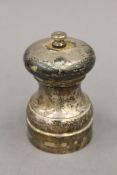 A silver pepper grinder. 10 cm high.