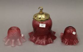Three cranberry glass light shades. The largest 23.5 cm high overall.