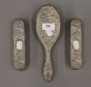 Three silver backed brushes. The largest 23.5 cm long.