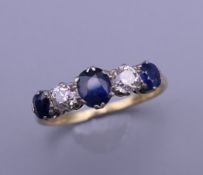 An 18 ct gold diamond and sapphire five stone ring. Ring size Q. 3 grammes total weight.