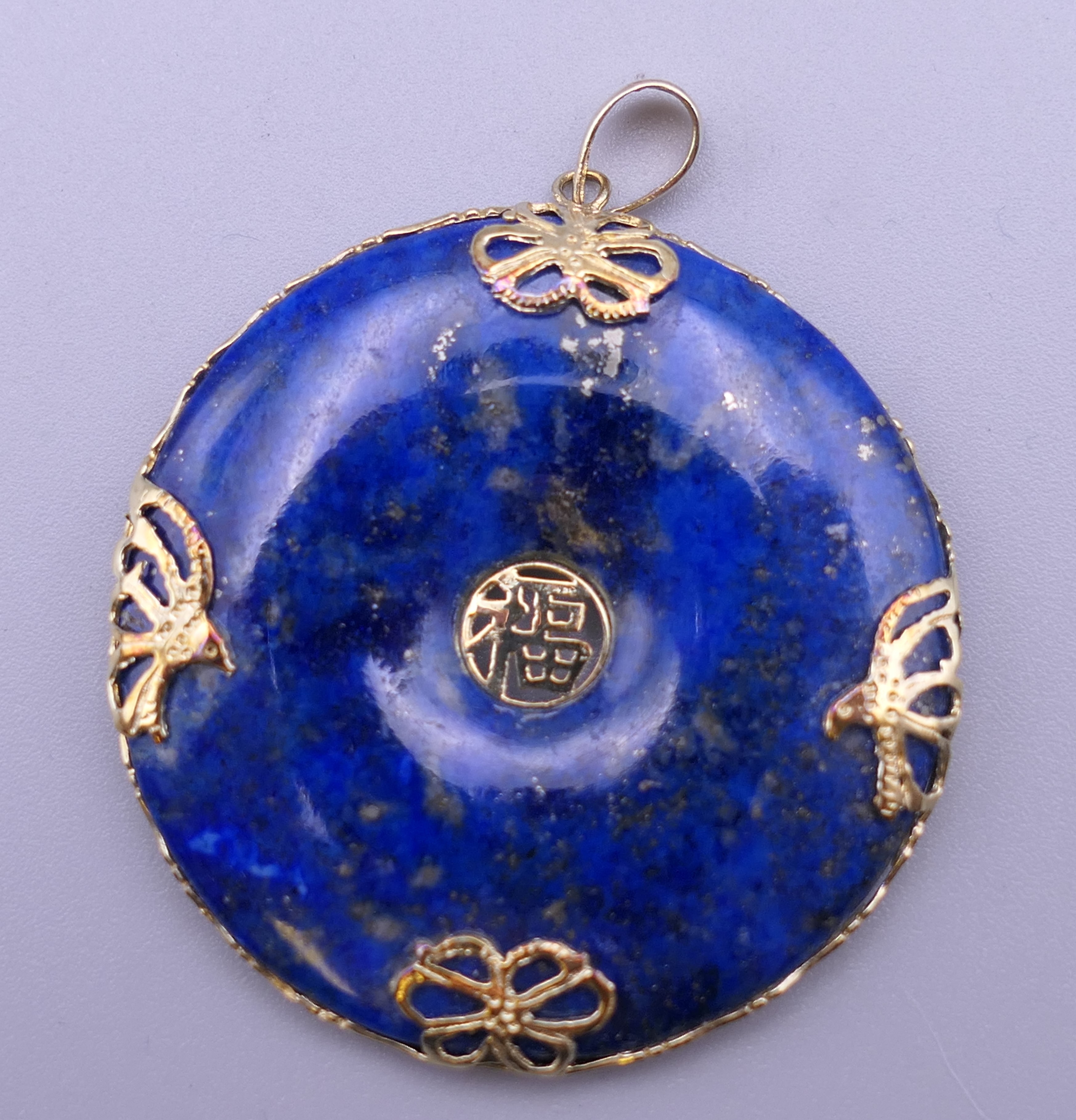 A Chinese 14 ct gold mounted lapis pendant. 3.5 cm diameter.