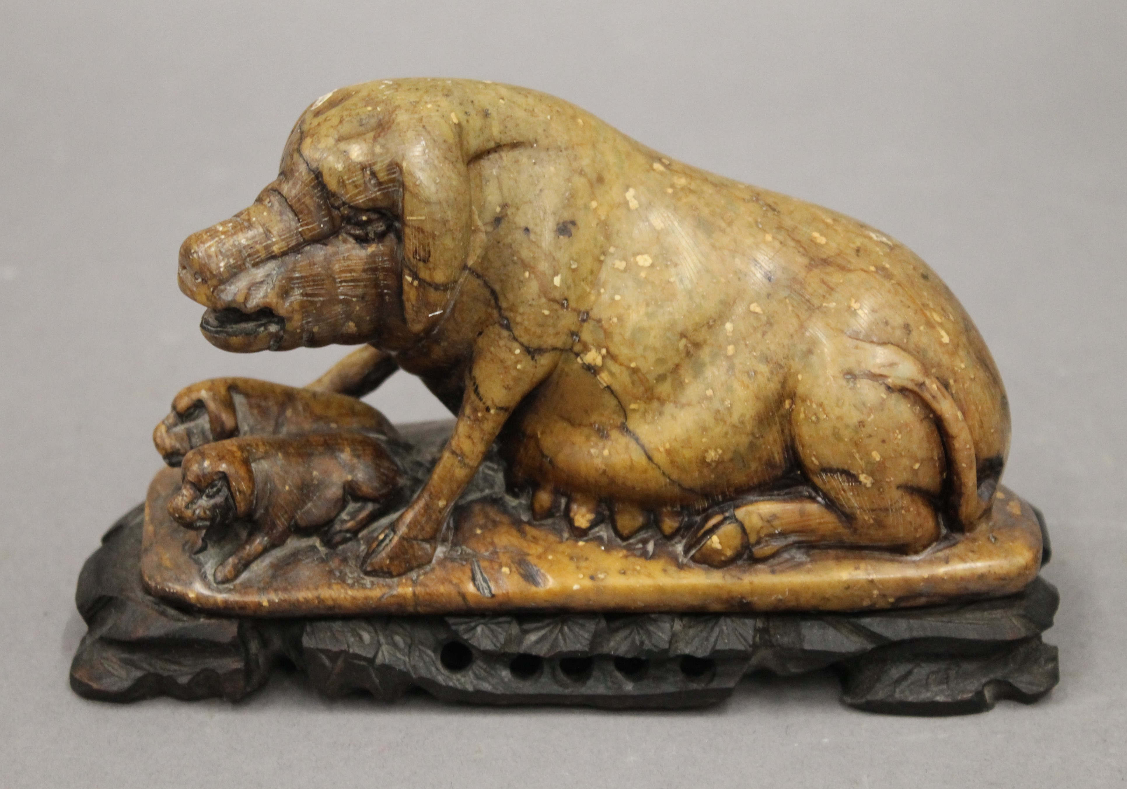 A Chinese soapstone carving of a sow and piglets, mounted on a wooden stand. 17 cm long overall.