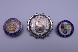 Two antique silver and enamel coin form brooches and a 1914 'On War Service' enamelled lapel badge.