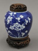 A small 19th century Chinese ginger jar with a wooden carved stand and lid. 15.5 cm high.