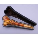 A cased 19th century meerschaum and amber pipe formed as a hand holding a pistol. 12 cm long.