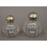 Two silver topped scent bottles. The largest 12 cm high.
