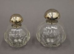Two silver topped scent bottles. The largest 12 cm high.