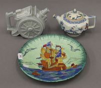 A 1930s tube lines wall plate of a galleon and two vintage teapots, one formed as a canon.